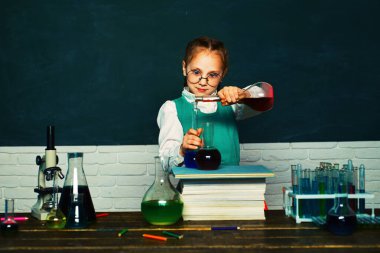 Laboratuvar mikroskobu ve test tüpleri. Sınıfta arka planda tahtası olan bir çocuk var. Mikroskop ile biyoloji deneyleri. Ders Planları - Ortaokul Kimya.