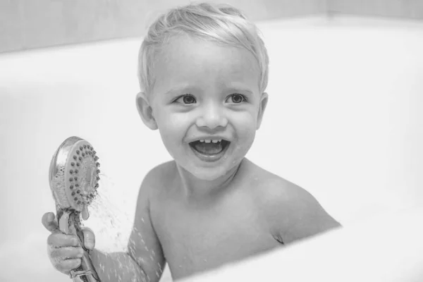 Een bubbelbad voor kinderen. Mooie glimlachende kleine jongen die een bad neemt met zeepcapsules. Leuke kleine jongen wassen. Kind in bad. — Stockfoto