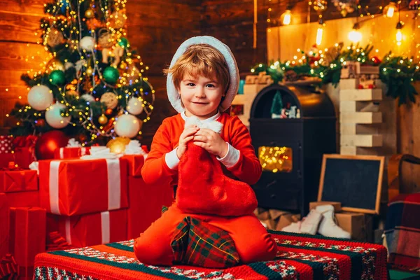 Kerstsok. Open Spelletjes. Een kleine jongen in warme kleren zittend en spelend met textiel speelgoed. Kerstwonder en nieuwjaarsgevoelens. Eerste herinnering aan de kindertijd. — Stockfoto