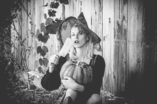 Kobieta z Halloween. Atrakcyjna wiedźma trzymająca dynię i nóż dla sztuczki lub psikusa. Kobieta ubieranie się w kostium Halloween z pomarańczowym kapeluszem czarownice na imprezę tematyczną. październikowy festiwal. Tło drewna. — Zdjęcie stockowe
