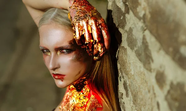 Halloween make-up. Trendy Halloween glowing gold skin make-up. Halloween Fashion art Golden skin Woman face portrait close-up. Halloween golden art design. — Zdjęcie stockowe