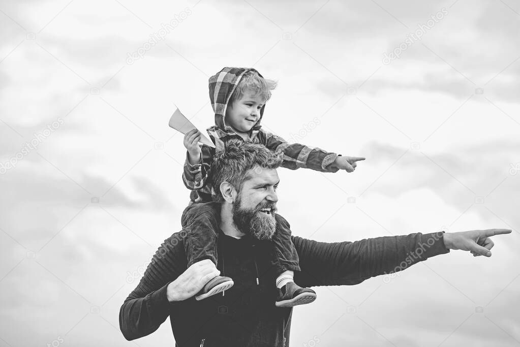 Happy fathers day. Dad and son are playing on sky background. Father and son building together a paper airplane. Portrait of happy father giving son piggyback ride on his shoulders and looking up