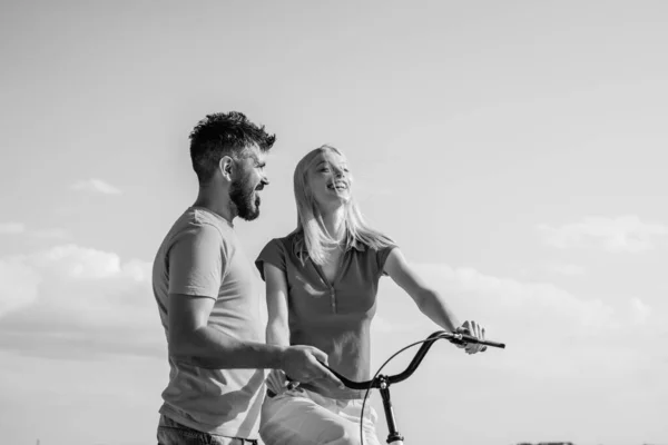 Summer woman with retro bike on blue sky background. Happy loving couple. Greatest Love Stories. Couple in summer dress rides a bike. Couple with vintage bike.