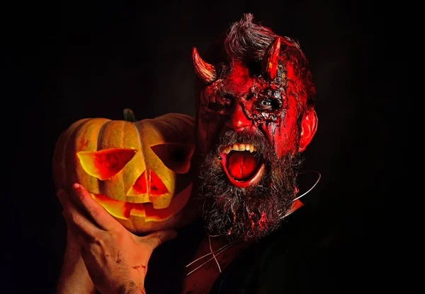 Halloween Devil with bloody professional makeup. Halloween bearded man with blood make-up. Funny character comic Dracula. Bearded man dressed like Halloween monster.