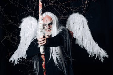Angelic bir adamın sanat fotoğrafı. Kıdemli adam melek kanatlarıyla poz veriyor. Kötü vampir adam. İblis suratlı harika bir büyücü adam. Siyah zemin üzerinde Druid.
