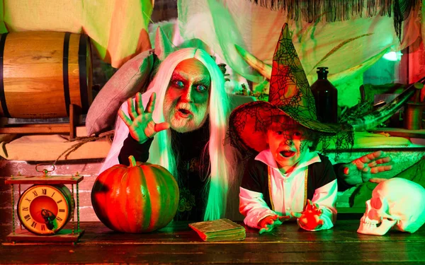 Vader en zoon spelen enge Halloween spelletjes thuis. Vader en zoon in carnaval kostuums wachten op gasten en snoep. Familie feest op Halloween. — Stockfoto