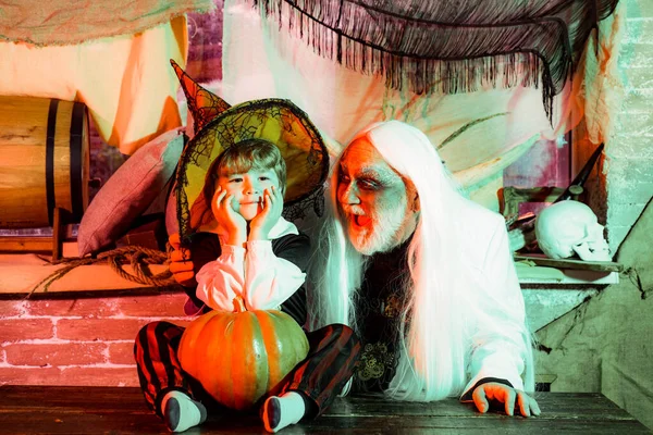 Papá y su hijo con disfraces de carnaval en el fondo de Halloween. Padre e hijo con disfraces de carnaval están esperando invitados y dulces. Fiesta familiar en Halloween . —  Fotos de Stock