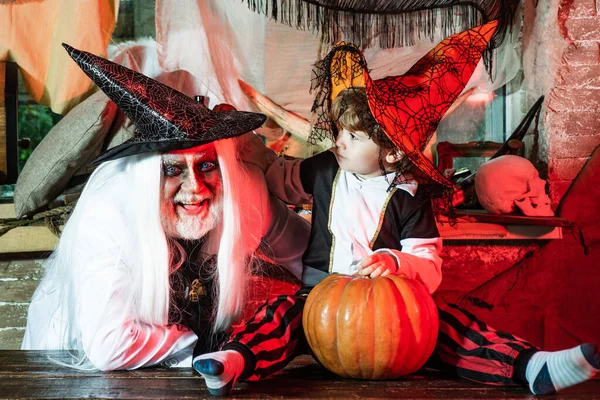 Father and son in carnival costumes are waiting for guests and sweets. Happy Father and Children boy in Halloween Costume. Happy family celebrate Halloween.