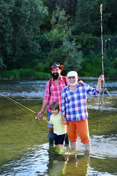 Nipote con padre e nonno che pescano in riva al lago. Ritratto di figlio, padre e nonno felice - tre generazioni di uomini che pescano sul fiume . — Foto Stock