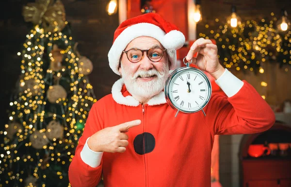 Santa Claus. Santa Claus drží hodiny s odpočítávání do Vánoc nebo Nového roku Santa Claus v dřevěném domácím interiéru ukazuje čas na hodinách. — Stock fotografie