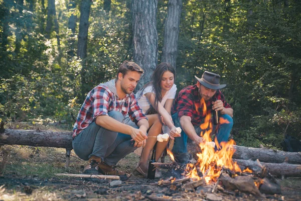 Empresa que tiene caminata picnic naturaleza fondo. Amigos asando perritos calientes en palos en la hoguera y divirtiéndose en el fuego del campamento. Amigos de la compañía pasan un gran tiempo de picnic o barbacoa cerca de la hoguera . —  Fotos de Stock