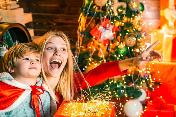 Lindo Ano Novo decorado em casa. A mãe sorrindo louca aponta com um dedo na janela para o filho. No Natal. Ano Novo. Véspera de Natal. Interior de Ano Novo brilhante . — Fotografia de Stock