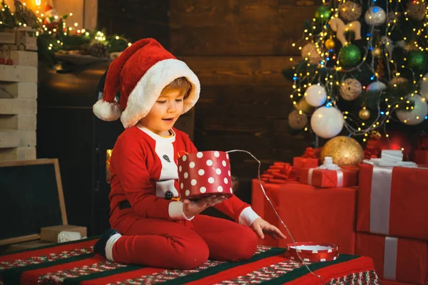 Ein überraschtes Kind mit fröhlichem Gesicht bekam ein Geschenk in der Weihnachtsbox. Freude und Glück Konzept. Weihnachten drinnen feiern. Weihnachtsmann, kleiner Helfer. Frohes neues Jahr und frohe Weihnachten. — Stockfoto