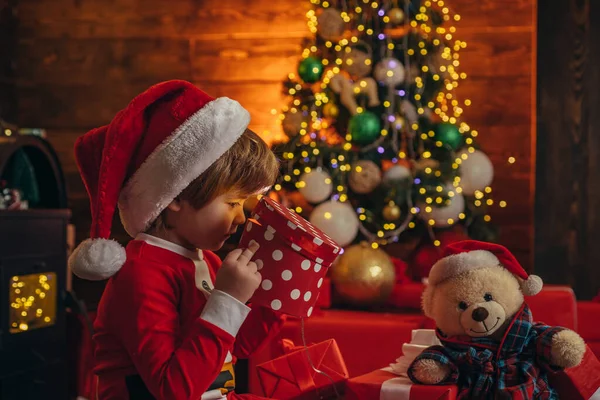 Weihnachtsinterieur. Neujahrsüberraschung Geschenk. Weihnachten. Frohes neues Jahr. Frohe Weihnachten. Kleines Genie. Kleiner Junge mit Weihnachtsmütze und Kostüm hat Spaß. — Stockfoto