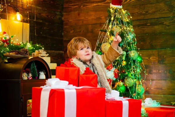 クリスマスプレゼントを開く陽気でかわいい子供。クリスマスギフトボックス付きの幸せな子供。冬の子クリスマスプレゼントを持っている面白い子供。かわいい子供が屋内でクリスマスツリーを飾る. — ストック写真