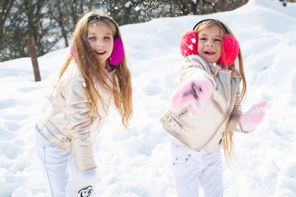 Bataille de boules de neige. Les enfants d'hiver s'amusent à jouer dans la neige. Les enfants lancent une boule de neige. Deux petites filles jouant sur la neige en hiver . — Photo