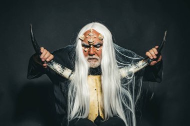 Ağaç ruhu ve fantezi konsepti. İblis suratlı harika bir büyücü adam. Beyaz mavi gözlü canavar. Korkunç cadılar bayramı adamı. Cehennemdeki Şeytan. Siyah zemin üzerinde Druid.