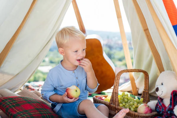 Lindo niño comiendo manzana al aire libre. Niño lindo juguetón alegre niño divertido mueca cara. Un chico acampando. Viajes . —  Fotos de Stock