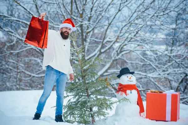 Frohe Weihnachten und ein gutes neues Jahr. Weihnachtsgeschäft oder Geschäft. Wintergefühle. Schneemann und lustiger Bärtiger mit Geschenk - die Freunde. — Stockfoto