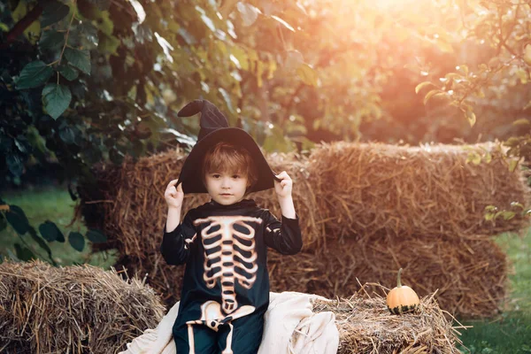 Halloweenskelet. Een jongen die op de hooiberg zit. Fijne dag. Klein kind geniet van wandelen. gelukkig lachen kind in kostuum naar halloween. — Stockfoto