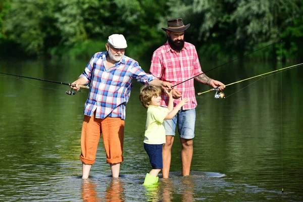 Generación familiar y concepto de personas. Padre enseñando a su hijo a volar peces en el río. Hombre en diferentes edades . — Foto de Stock