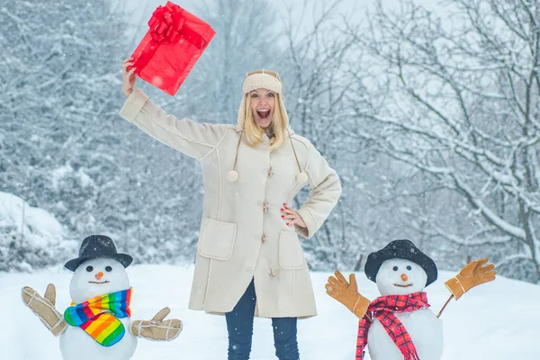 Modelo femenino divertido posando en el clima de invierno. Lindos muñecos de nieve con chica de invierno de pie en invierno Navidad paisaje . — Foto de Stock