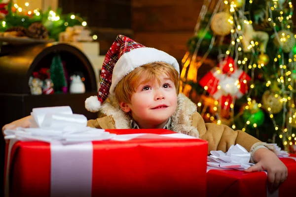 Glada barn som håller i en gigantisk röd presentask med båda händerna. Julgrabbar. Nyårsungar. Rolig grabb som håller julklapp. — Stockfoto