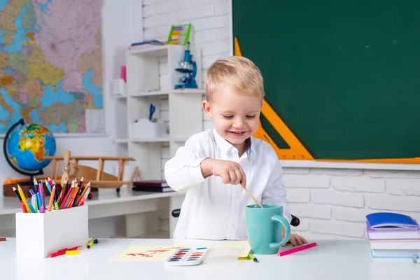 笑顔の少年が学校の教室で宿題をしている姿が描かれている。教育. — ストック写真