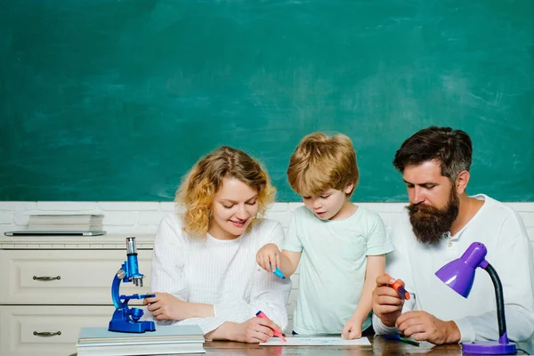 Elementary student. Parents encouraging their little son before the first day of school. Young couple helping his son to make homework. Beginning of lessons. School concept.