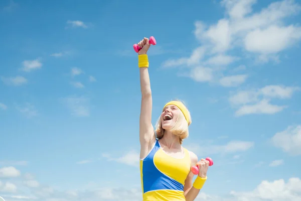 Joven hermosa chica deportiva de entrenamiento al amanecer sobre el cielo. Mujer de fitness. Hermosa joven con mancuernas en sus manos hace fitness . —  Fotos de Stock