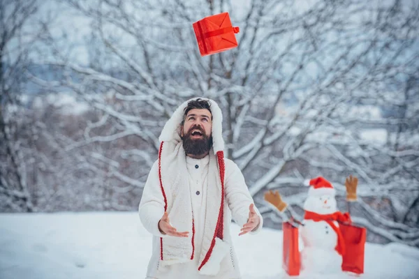 De Kerstman wenst een vrolijk kerstfeest. Hipster Kerstman. Kerstmis en nieuwjaarsvakantie. Gelukkig vader spelen met een sneeuwpop op een besneeuwde winterwandeling. — Stockfoto