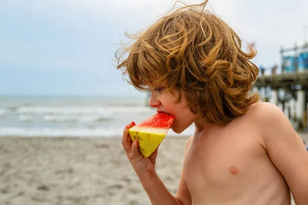 Niño en el mar con sandía. Sabor de verano. Lindo niño sosteniendo sandía mientras está de pie en la playa de verano . —  Fotos de Stock