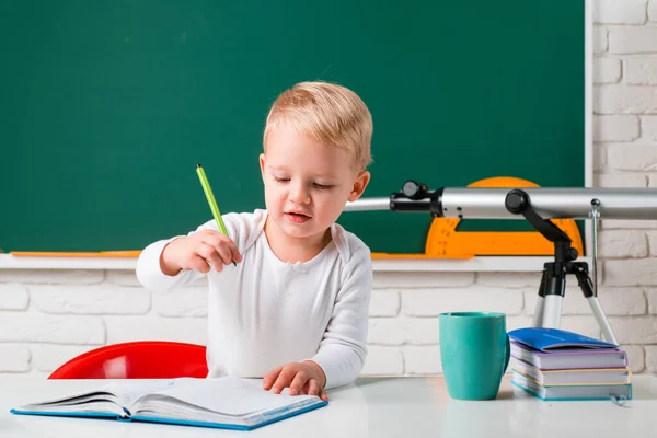 緑の黒板に反対する学校の子供たち。小さな学生の少年は素晴らしいマークで幸せ。幸せなかわいい勤勉な子供は屋内の机に座っています. — ストック写真