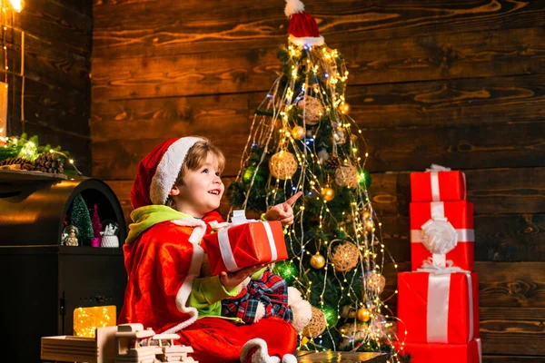 Neujahrskinder. Glückliche süße Kind in Weihnachtsmütze mit Geschenk haben ein Weihnachten. Glückliches Kind mit Weihnachts-Geschenk-Box. — Stockfoto