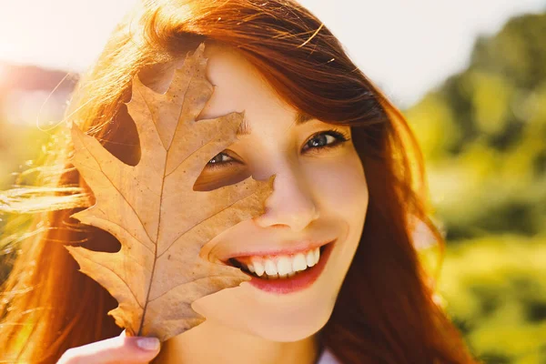 Őszi nő élénk narancssárga hajjal. Meleg napos idő. Őszi koncepció. Őszi levelek hullanak boldog fiatal nőkre az erdőben. Boldog mosolygós lány természetes vörös hajjal. — Stock Fotó