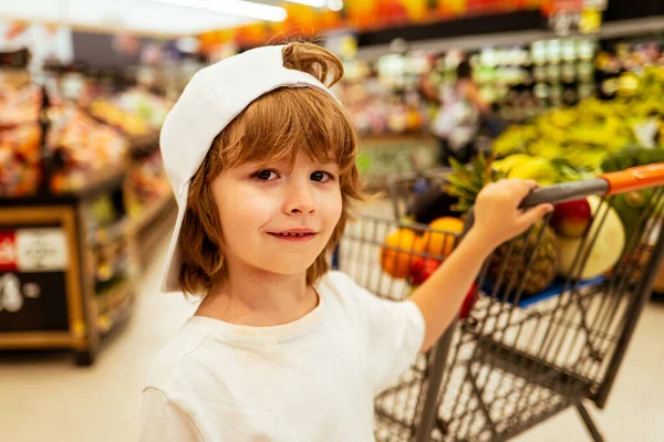 Bambini che fanno shopping. Gioioso bel bambino ragazzo nel supermercato compra verdure. Cibo sano per bambini . — Foto Stock