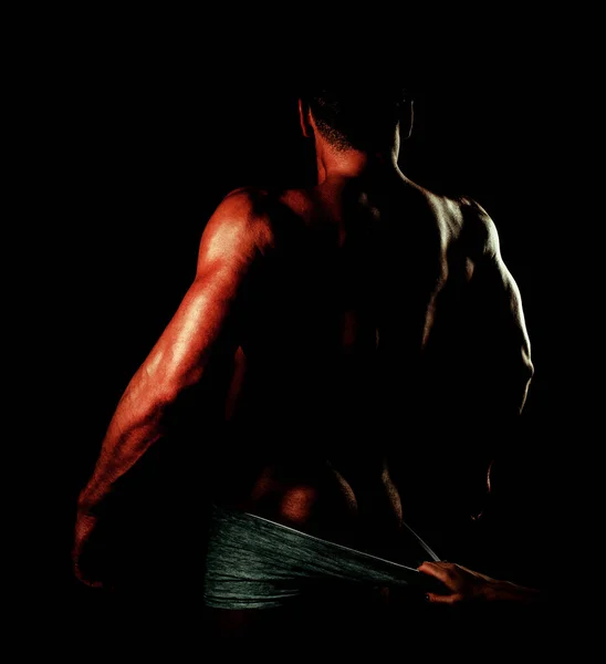 Kobieta rozbiera spodnie. Brutalny facet z seksownym, nagim tułowiem. Muskularny model człowieka na ciemnym tle. Koleś. Człowiek muskularny. — Zdjęcie stockowe