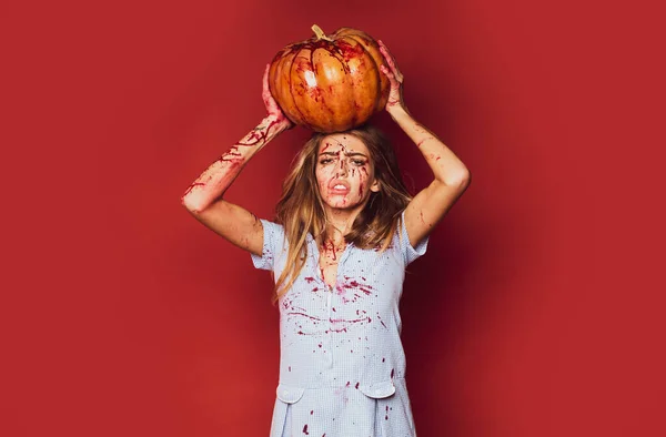 Mujer de Halloween sobre fondo rojo aislado. Chica con calabaza. Sangre en la cara . — Foto de Stock