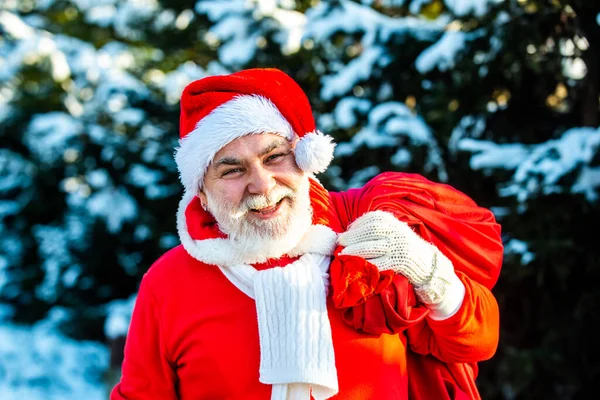Télapó jön a téli erdőben egy zsák ajándékot hótáj. Karácsony este a Mikulás ajándékokat visz a gyerekeknek egy piros zsákban.. — Stock Fotó