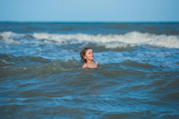 Doğada deniz, kum ve mavi gökyüzü olan bir çocuk. Yaz tatili ve tatil konsepti.