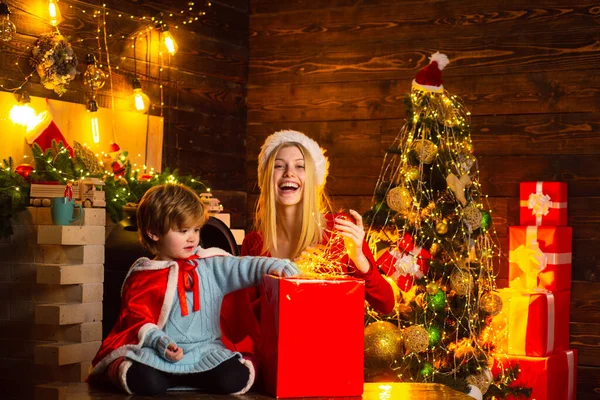 O Natal está a chegar. A mulher e o rapazinho estão a abrir a caixa com luz de Natal. A decorar a árvore de Natal. Decoração em casa antes do Natal . — Fotografia de Stock