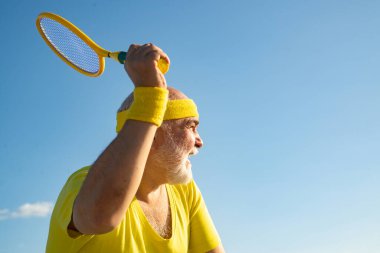Tenis eğlencelidir. Kıdemli tenisçi servis yapıyor. Sağlıklı ve spor. Spor ve emeklilik kavramı.