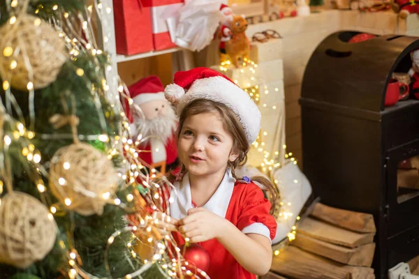 Weihnachtskind mit Christbaumkugel oder Weihnachtskugel dekorieren. Weihnachtsspielzeug - Mädchen schmückt den Weihnachtsbaum. — Stockfoto