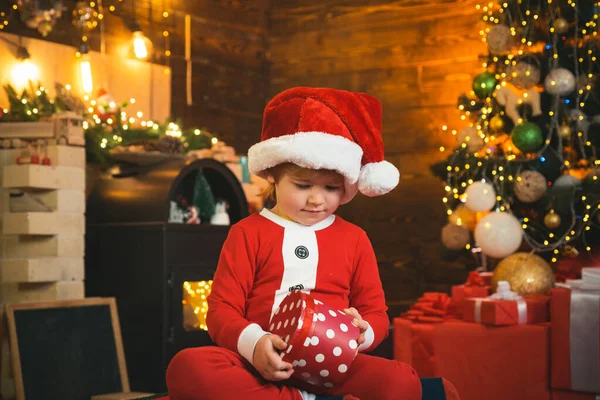 Juldekorationer. Lyckligt barn med julklapp. Nyårsungar. Nytt årskoncept. Barn med en julklapp på trä hus bakgrund. — Stockfoto