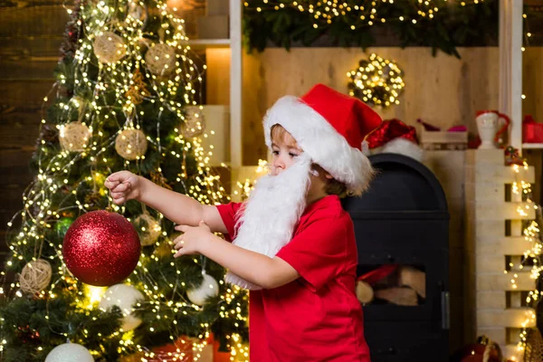 Leuke jongen die kerstboom versiert. Gelukkig kind met kerstbal. Leuke kleine kinderen die Kerstmis vieren. Gelukkig schattig kind in Santa hoed met kerstbal hebben een kerst. — Stockfoto