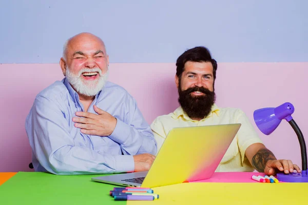 2人のビジネスマンが職場で大声で笑っている。2人のサラリーマンがノートパソコンで面白いコンテンツを見て笑っていました。彼らの成功を祝う2つの幸せな成熟したビジネスマン. — ストック写真