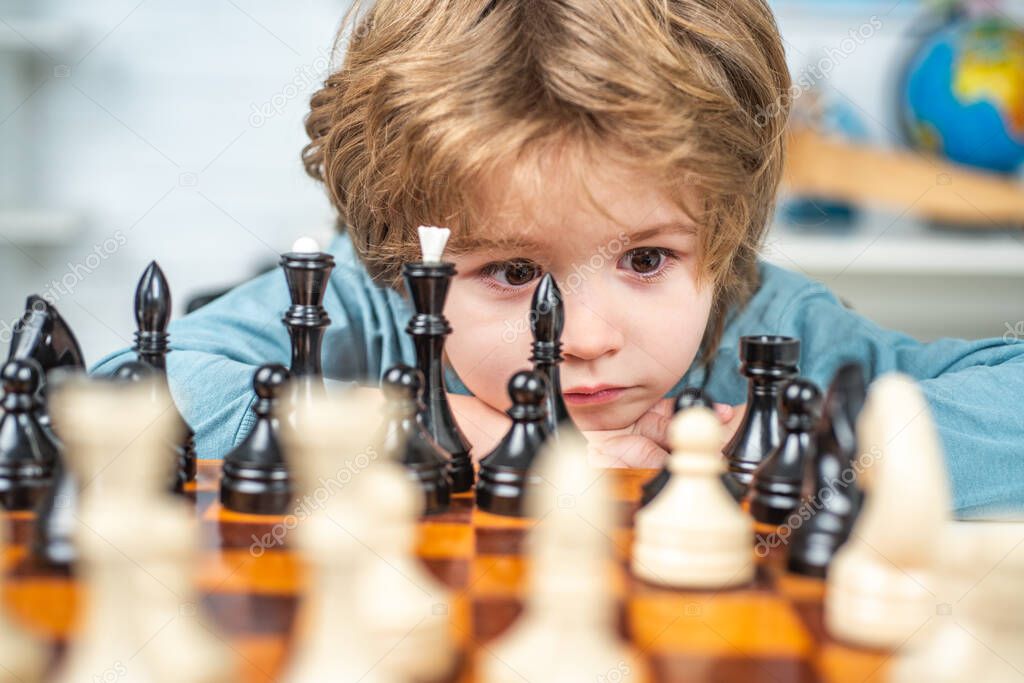 Little boy playing chess. Boy kid playing chess at home. Clever concentrated and thinking child while playing chess. Portrait close up, funny face.