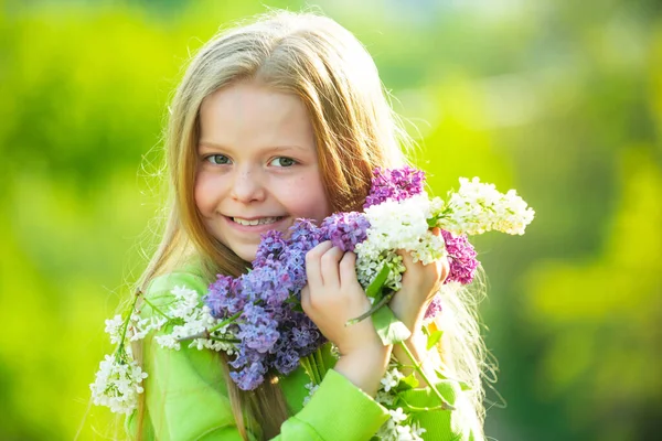 有紫丁香的少女。春姑娘在盛开的花园里.美丽微笑的少女的户外肖像. — 图库照片