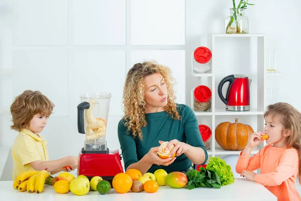 Retrato de família bonito está fazendo suco de frutas. na cozinha branca. Alimentos saudáveis em casa . — Fotografia de Stock