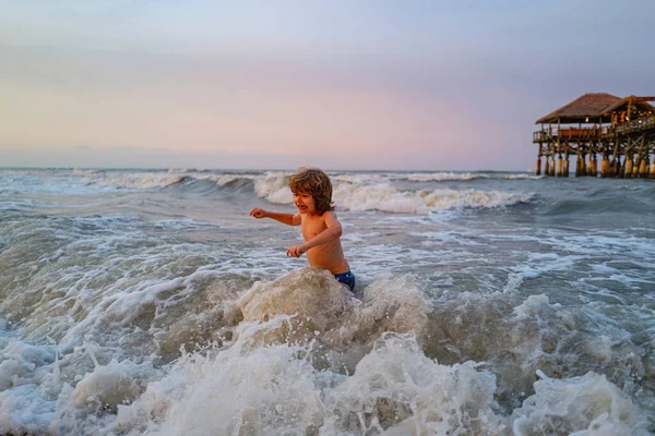 Océano azul con grandes wawes blancos en el fondo. Niños en la naturaleza con hermoso mar, arena y cielo azul. Niño aprendiendo a nadar al aire libre. Vacaciones de verano y concepto de viaje . — Foto de Stock